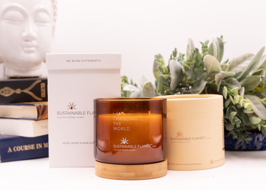 Candle jar and packaging on a tabletop with foliage and books